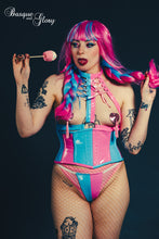 Load image into Gallery viewer, Person with pink and blue hair and tattoos wearing a colorful outfit against a dark background.
