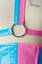 Load image into Gallery viewer, Close-up of a pink and blue harness with a metal ring on a beige background.
