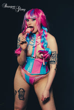 Load image into Gallery viewer, Person wearing a colorful outfit with suspenders and a microphone against a dark background
